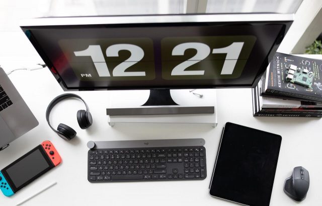 Puesto de trabajo organizado con un monitor de sobremesa conectado a un portátil, acompañado de una mesa y auriculares